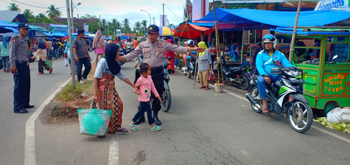 Team Ops. Binakusuma Singgalang 2019, Polres Sijunjung, sedang memandu pengunjung pasar saat menyeberang  jalan